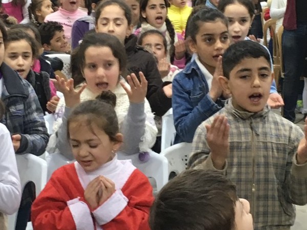 Iraqi refugee children pray for their meals on Iraq during the Christmas for Refugees program