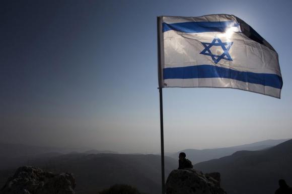 Israeli soldier stands guard under an Israeli national flag during a tour made by Israeli parliament members in the Jordan Valley near the Jewish settlement of Maale Efrayim